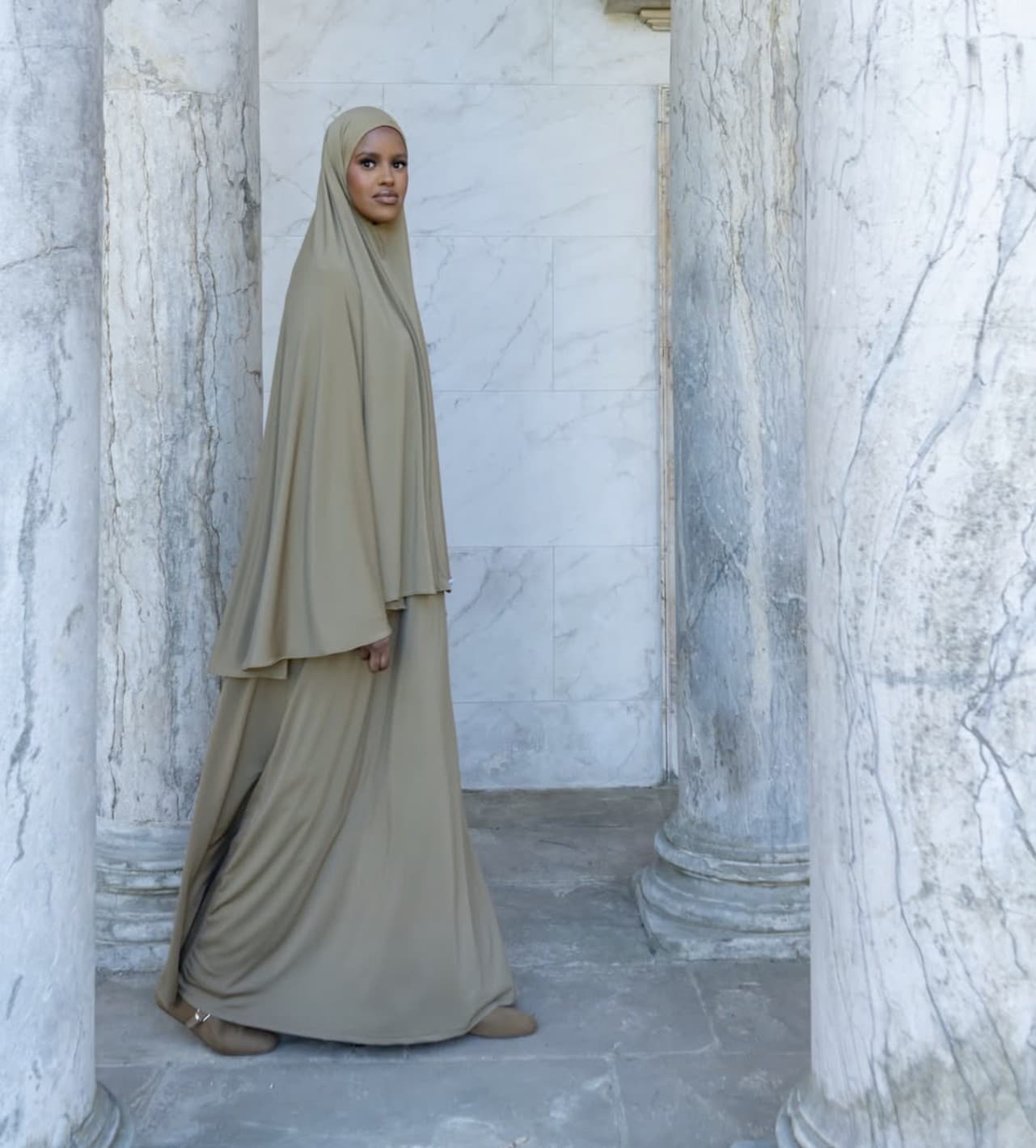 Woman wearing a modest jilbab set standing among classical columns